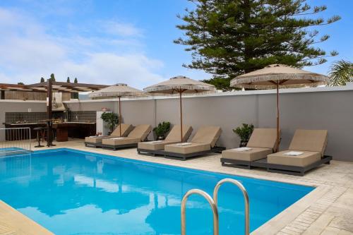 a swimming pool with lounge chairs and umbrellas at Pervolia House Private Pool Near Airport in Kremasti