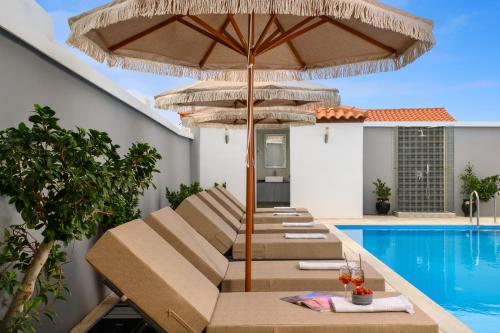a group of chairs under an umbrella next to a swimming pool at Pervolia House Private Pool Near Airport in Kremasti