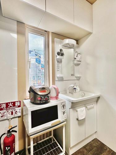 a small kitchen with a microwave and a sink at 北海道大学ENYA-n17 in Sapporo