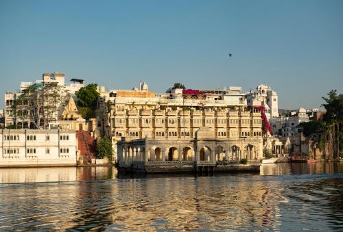 a large building on the water next to a city at Minimalist - Lake Pichola Edit in Udaipur