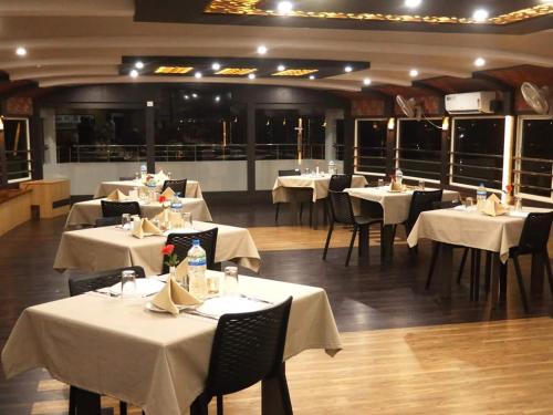 a restaurant with tables and chairs with white table cloth at Hills & Cruise Luxury Houseboats in Alleppey