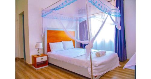 a bedroom with a canopy bed and a window at Breeze House Hotel in Kigali