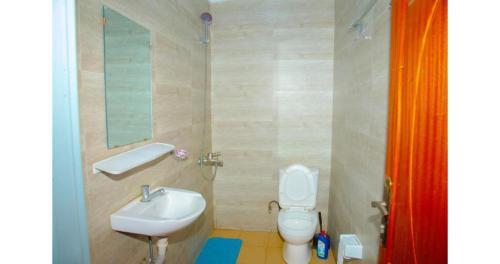 a bathroom with a sink and a toilet and a mirror at Breeze House Hotel in Kigali