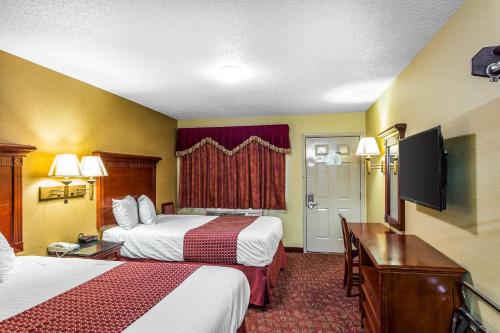 a hotel room with two beds and a flat screen tv at Rodeway Inn Goodlettsville South in Goodlettsville