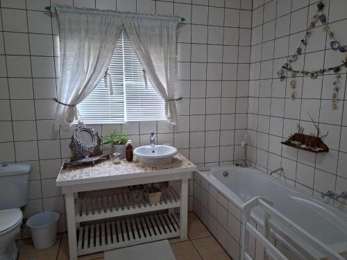 a bathroom with a sink and a tub and a window at DolfinHouse in Yzerfontein