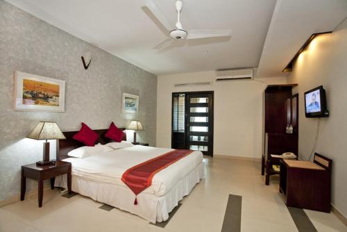 a bedroom with a large white bed and a television at Well Park Residence in Chittagong