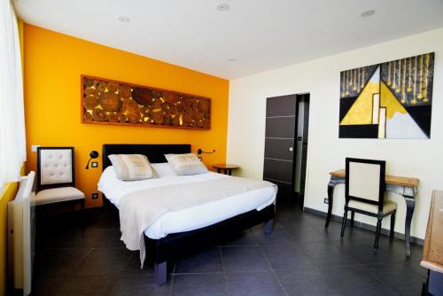 a bedroom with a bed and a table and chairs at Logis Hôtel Restaurant Chez Nous in Sainte-Croix