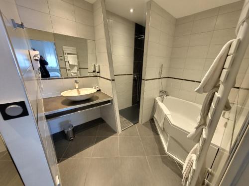 a bathroom with a tub and a sink and a bath tub at Logis Hôtel Restaurant Chez Nous in Sainte-Croix