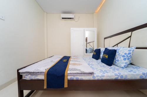 a bedroom with a bed with blue pillows at Tempuran Suites By ARBA in Kejayan