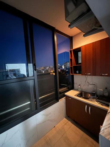 a kitchen with large windows with a view of the city at Ajsi Apartments in Durrës