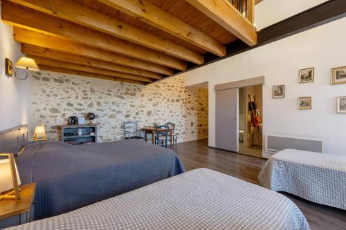 a bedroom with two beds and a table with chairs at Chambres D'hôtes Les Carmes in La Flocellière