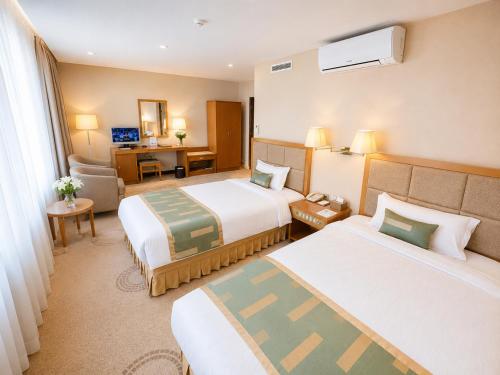 a hotel room with two beds and a desk at Flower Hotel Ulaanbaatar in Ulaanbaatar