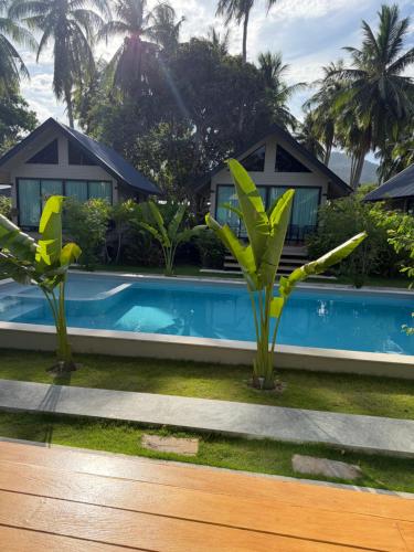 a villa with a swimming pool and palm trees at Good Mood Bungalows in Ko Phangan