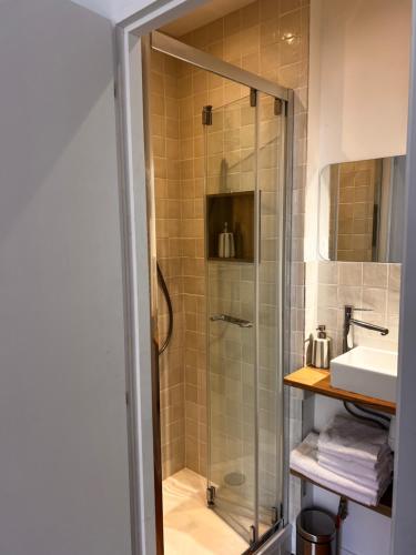 a shower with a glass door next to a sink at Charmant 2 pièces - centre historique - Vieux Mans in Le Mans
