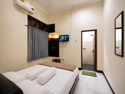 a bedroom with a large white bed and a television at Abadi Homestay Yogyakarta in Yogyakarta