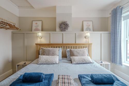 a bedroom with a large bed with blue pillows at Beachcomber, Dog-Friendly Coastal Cottage Close to the Beach in Winterton-on-Sea