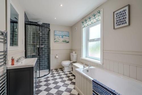 a bathroom with a tub and a sink and a toilet at Beachcomber, Dog-Friendly Coastal Cottage Close to the Beach in Winterton-on-Sea