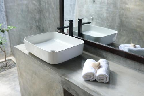a bathroom with a sink and a mirror and towels at Aji fruit farm cottage peaceful lakeside farm stay with sunrise views 01 in Embilipitiya