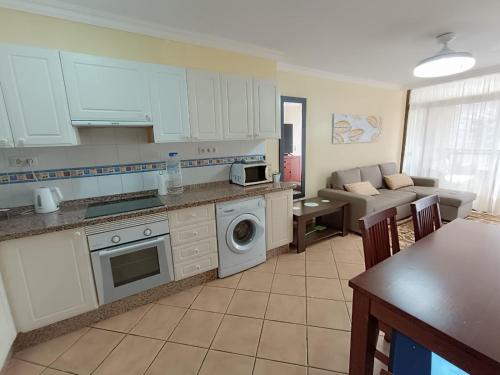 a kitchen with white cabinets and a living room at Apartmán Centrum in Los Cristianos