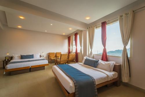 a hotel room with two beds and a window at Tripli Hotels M & Resort in McLeod Ganj