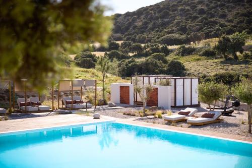 a pool with chairs and a mountain in the background at Golden Milos Beach Ηouse by Domotel in Provatas