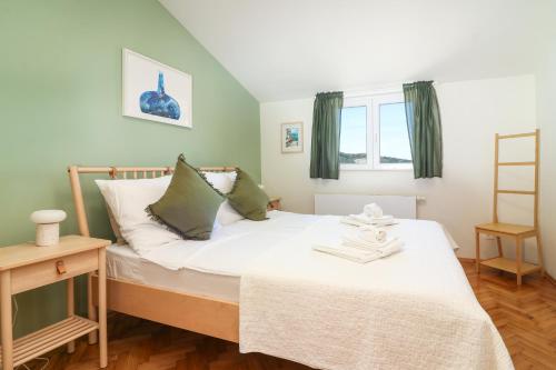 a bedroom with a bed with white sheets and green curtains at D&J Apartments in Primošten