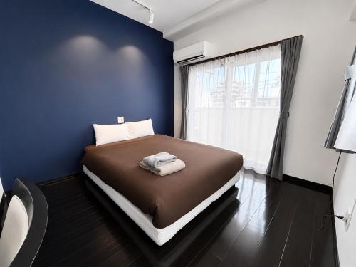 a bedroom with a bed with a blue wall and a window at Luana Uakoko Resort 旧 EmiFull Resort in Chatan
