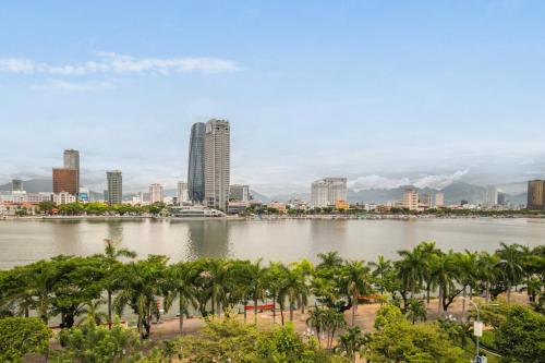 a large body of water with palm trees and buildings at Ngoc Thuong Hotel & Apartment- Han River View in Danang