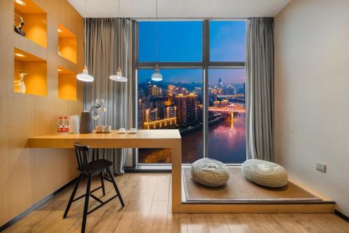 a room with a desk and a window with a view at ChongQing BackHome Riverview Hotel in Chongqing