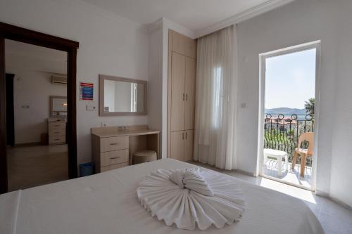 a bedroom with a white bed with a large window at Gokcen Hotel & Apartments in Oludeniz
