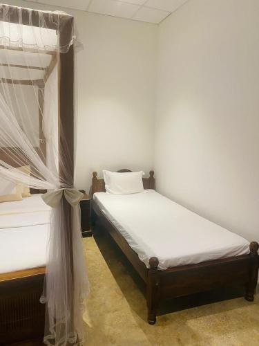 a bedroom with two beds and a canopy bed at Ceylon Kingsmen Garden - Katunayake Airport Transit Hotels in Negombo