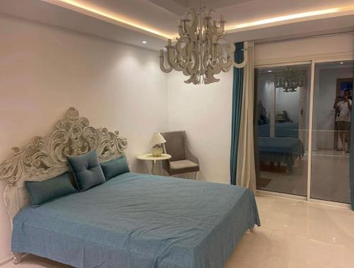 a bedroom with a blue bed and a chandelier at Beautiful villa with pool KELIBIA in Kelibia