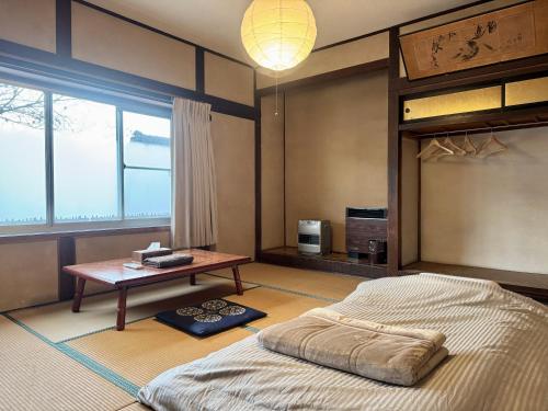 a bedroom with a bed and a table and a window at 北アルプス麓のゲストハウス林屋 in Omachi