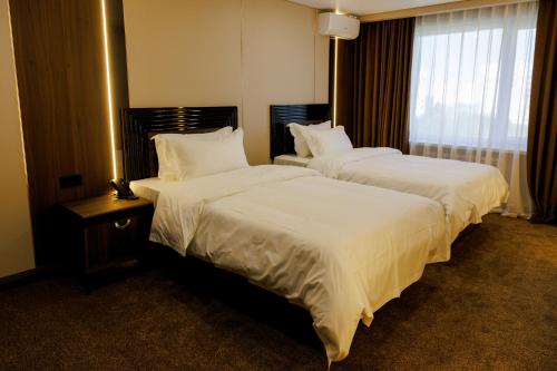 two beds in a hotel room with white sheets at Air Kostanay in Kostanay