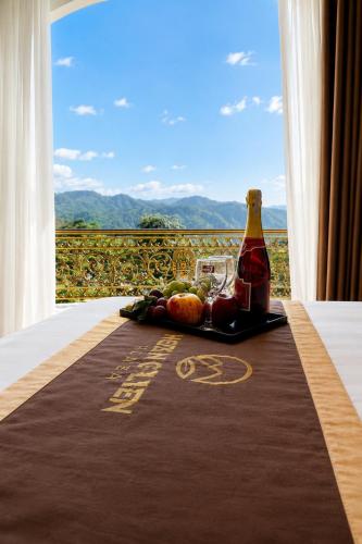 a bottle of wine and fruit on a table with a window at Hoàng Liên Hotel in Na Cốc