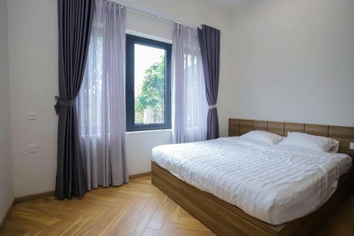 a bedroom with a large bed and a window at Flora Garden in Làng Hang