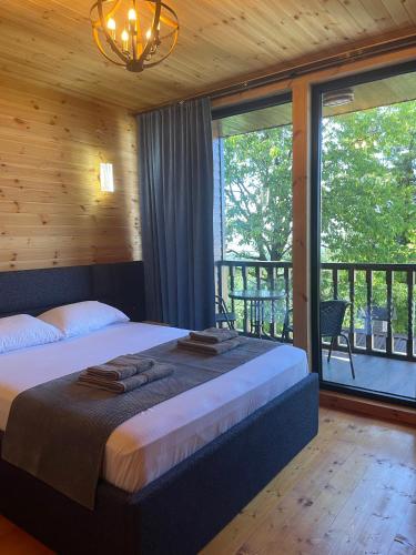 a bedroom with a large bed and a balcony at GrapeHill Cottage in Achʼqva
