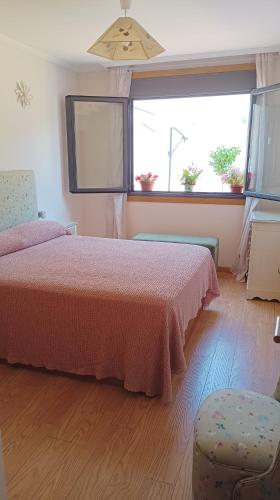 a bedroom with a bed and a chair and two windows at Apartamento La Camelia in Rosal