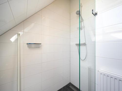 a shower in a white tiled bathroom at Aan Noordzee Villa Veranda huisdier toegestaan max 2 in Sint Maartensvlotbrug