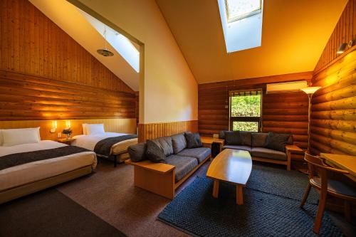 a hotel room with two beds and a couch at Log Hotel The Maple Lodge in Iwamizawa