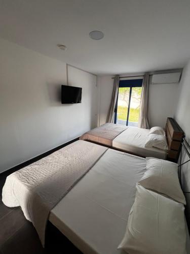 two beds in a room with a tv on the wall at Salt & Sea in Sykia Chalkidikis
