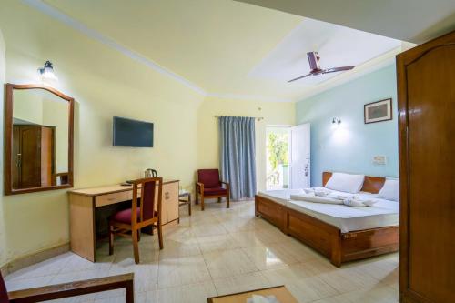 a bedroom with a bed and a desk and a mirror at Farmagudi Residency in Ponda