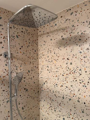a shower in a bathroom with a wall covered in rocks at Oravelle Loft Kubin in Dolný Kubín