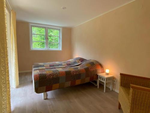 ein Schlafzimmer mit einem Bett, einem Fenster und einem Tisch in der Unterkunft Magical hide-away in the forest in Trensum