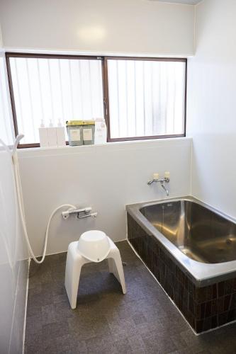 a bathroom with a tub and a stool next to a sink at Knot Kyonan in Katsuyama
