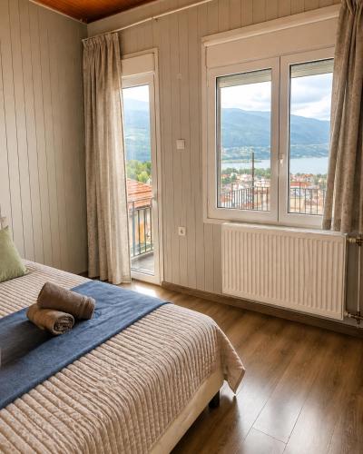 a bedroom with a bed and two large windows at Skyline apartment Ioannina in Ioannina