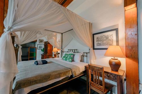 a bedroom with a canopy bed and a table with a lamp at Sikepan Villa Borobudur in Mendut