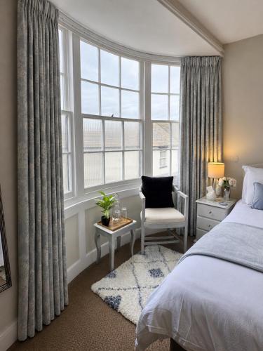a bedroom with a bed and a chair and a window at The Wadham in Weymouth