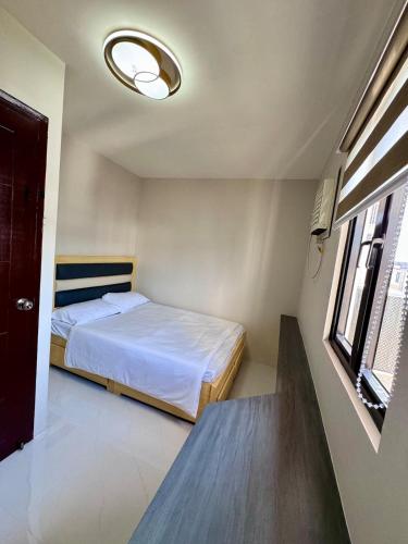 a small bedroom with a bed and a window at Idesia Lipa Custodio Suites in Lipa