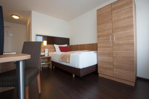 a hotel room with a bed and a desk and a desk at Centro Hotel U-NO1, Trademark Collection by Wyndham in Großbettlingen
